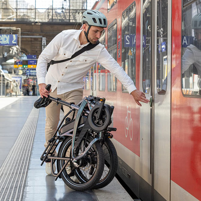 A man rolling a fold-up Vektron e-bike at the metro station to onboard the train.