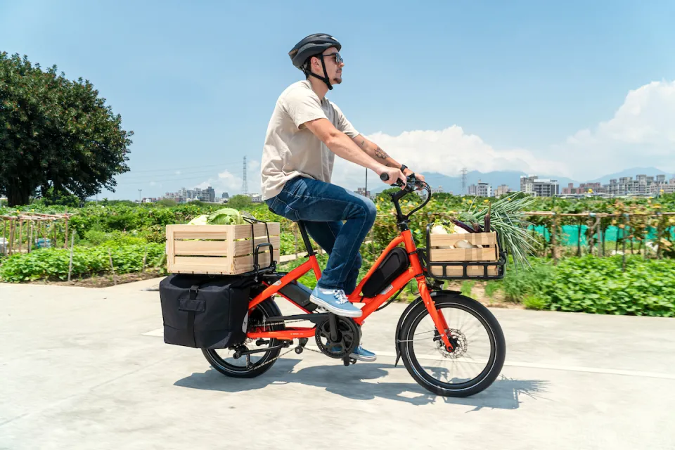 Man riding a Tern Quick Haul e-cargo bike while carrying crates