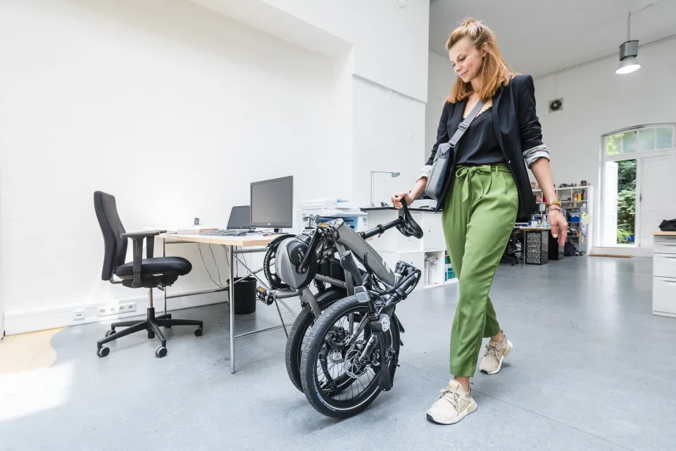 Woman rolling a Tern Vektron folding e-bike into her office