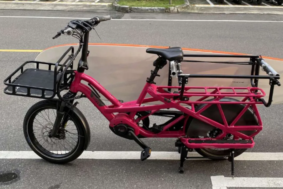 Tern GSD electric cargo bike carrying a surfboard on the side, attached to the Clubhouse passenger rails and Transporteur Rack in the front.