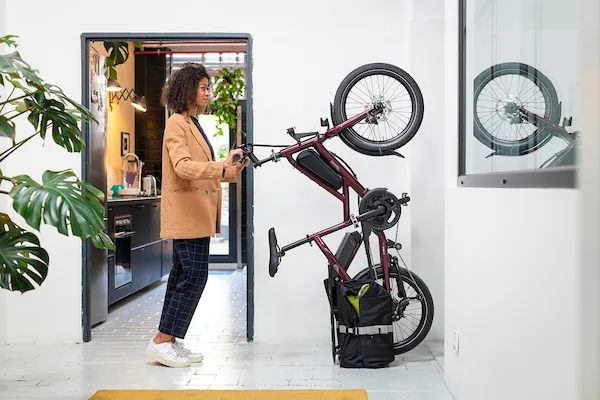 A woman vertically parking her Tern Quick Haul Long electric cargo bike in the corner of her living room.